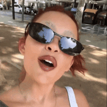 a woman wearing sunglasses is making a face