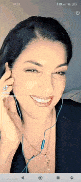 a woman wearing earphones and a cross necklace is smiling