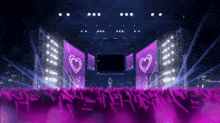 a crowd of people watching a concert with purple lights and hearts