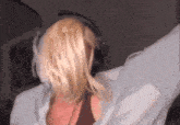 a woman with blonde hair wearing headphones and a white shirt is dancing .