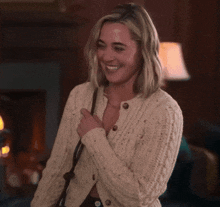 a woman wearing a cardigan is smiling and holding her purse