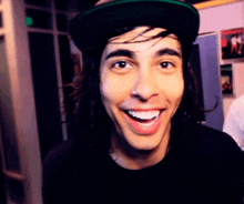 a man wearing a black shirt and a green hat smiles