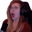 a woman wearing glasses and headphones is sitting in front of a microphone with her mouth open .