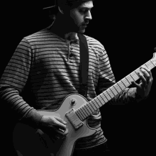 a man in a striped shirt is playing a white guitar