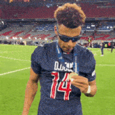a soccer player wearing sunglasses and a jersey with the number 14