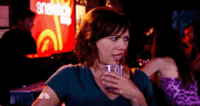 a woman drinking from a straw in front of a sign that says snapple
