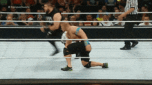 two men are wrestling in a ring with a crowd behind them and a referee standing behind them