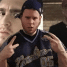 a man wearing a blue jersey with the number 05 on it is making a peace sign .