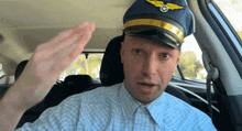 a man wearing a pilot 's hat is waving his hand