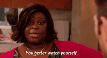 a woman is talking to a man in a kitchen and saying `` you better watch yourself . ''