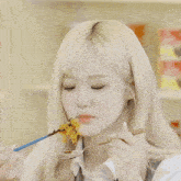 a blonde girl is eating noodles with chopsticks