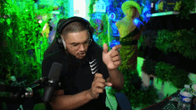 a man wearing headphones and a t-shirt that says ' nike ' on it stands in front of a microphone