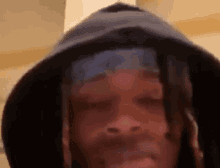 a man with dreadlocks is wearing a hooded hat and a bandana around his head .