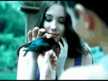 a woman is holding a bird in her hand