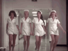 a group of nurses are dancing together in a hospital hallway .
