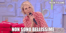 a woman is sitting on a couch holding a microphone and saying non sono bellissime