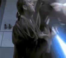 a man in a robe is holding a blue light saber in his hand .