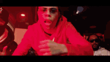 a man in a red hoodie is standing in a kitchen with red lights