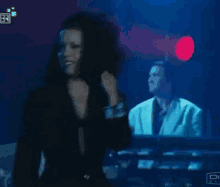 a woman with curly hair is standing in front of a man playing a keyboard .