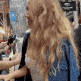 a woman in a denim jacket is being interviewed by a man in front of a sign that says buddie bar