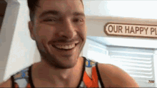 a man is smiling in front of a sign that reads our happy place