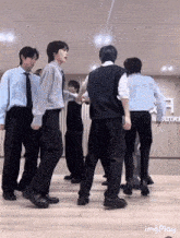 a group of young men in suits and ties are dancing together in a dance studio .