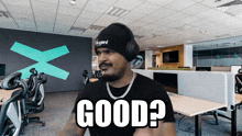 a man wearing headphones and a beanie says " good "