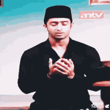 a man praying in front of a sign for antv