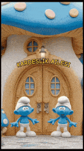 two smurfs are standing in front of a house that says kardeslik ailesi on it