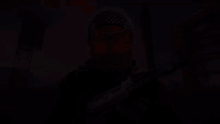 a man wearing a mask and holding a gun with a red light on his face