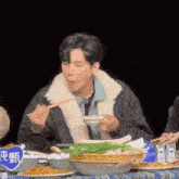 a man eating food with chopsticks in front of a sign that says ' chinese ' on it