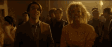 a man and a woman are standing in a crowd of people at a party .