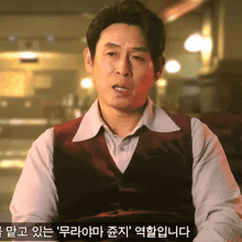 a man wearing a red vest and a white shirt is talking in a foreign language