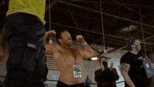 a shirtless man flexes his muscles while wearing a lanyard with a badge that says 3.62