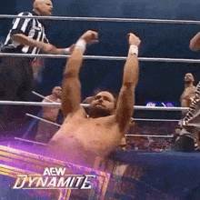 a man is hanging upside down in a wrestling ring with his arms in the air and the words aew dynamite behind him