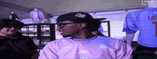 a man wearing a pink kappa shirt stands in front of a display of jerseys
