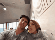 a man and a woman are posing for a picture and the woman is sticking out her tongue