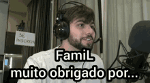 a man wearing headphones is sitting in front of a microphone with the words famil muito obrigado por written above him