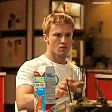 a man sitting at a table with a carton of rice milk