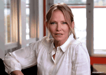 a woman in a white shirt is sitting in front of a window with the words squadbot behind her