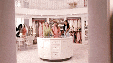 three women are standing in a large closet with a round island in the middle