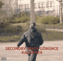 a man is walking in a park with the words secondary erkek gorunce kacarken