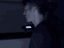 a man in a dark room looking at a phone that says ' netflix ' on it