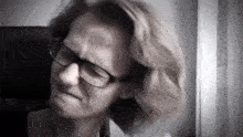 a woman wearing glasses is making a face in a black and white photo .
