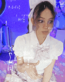 a girl wearing a white shirt and a bow tie is sitting on a bed with mathematical equations written on the wall