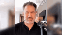 a man with a beard is talking into a microphone in a room .