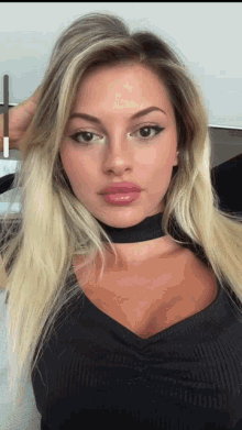 a woman with blonde hair and a choker around her neck looks at the camera
