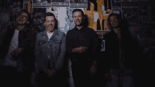 a group of men standing in front of a wall with posters on it including one that says wednesday