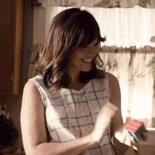 a woman in a plaid shirt is smiling while holding a red cube .