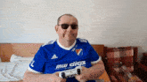 a man wearing sunglasses and a blue shirt that says mw clics
